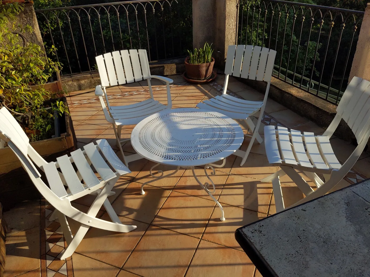 Salon de jardin en fer, table et chaises repeintes en blanc sur une terrasse